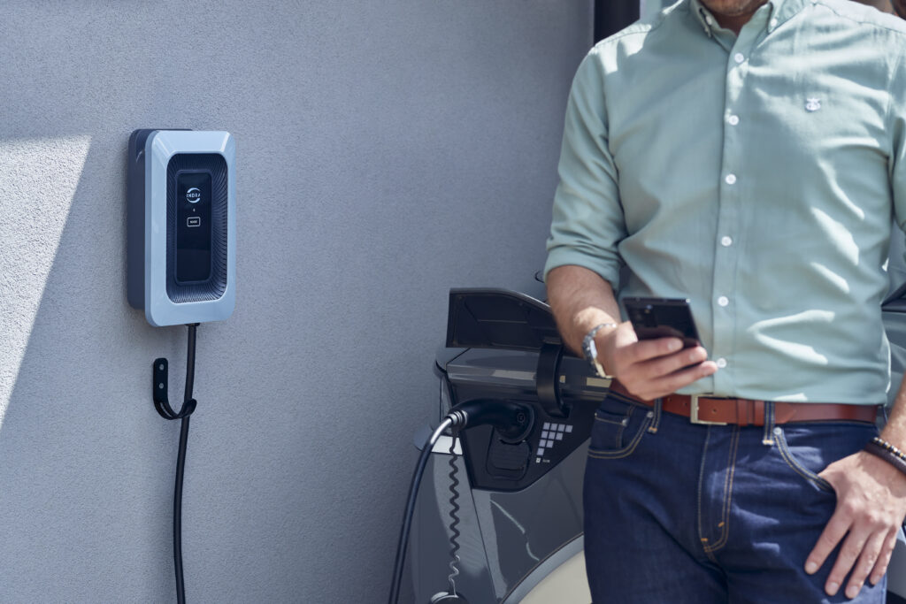 Man on phone in front of EV and charger