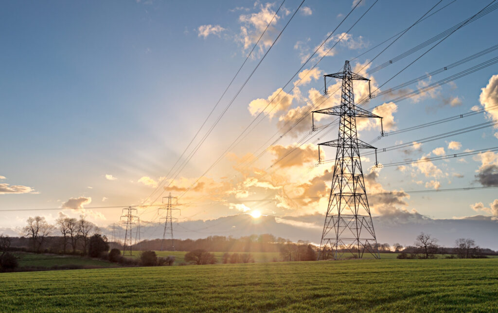 power cables across a landscape with sun rising in the background