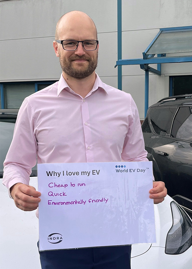 Man in pink shirt and glasses holding a sign