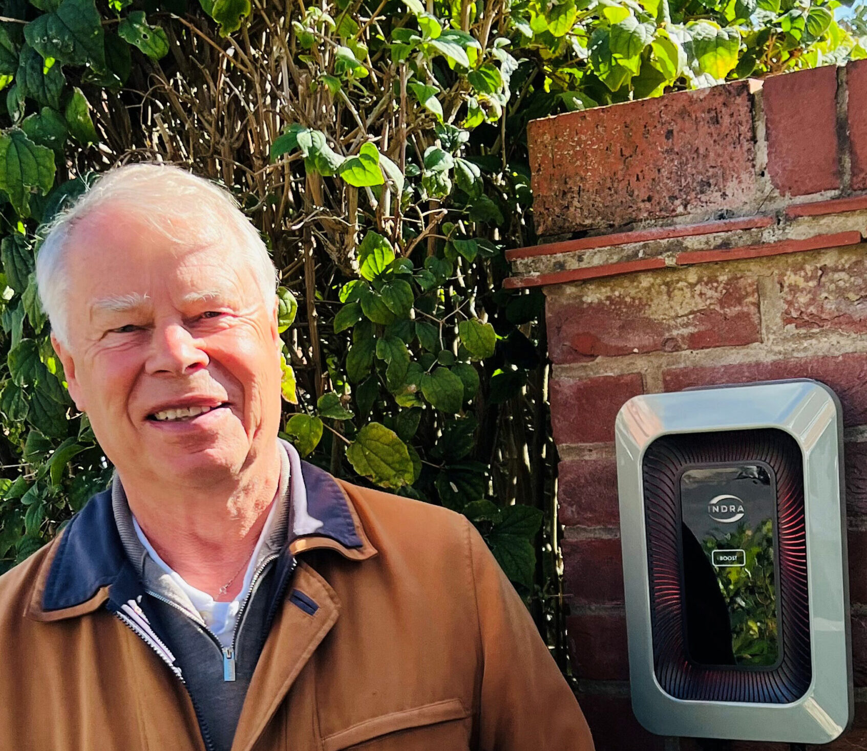 Man standing by an Indra LUX charger on a wall
