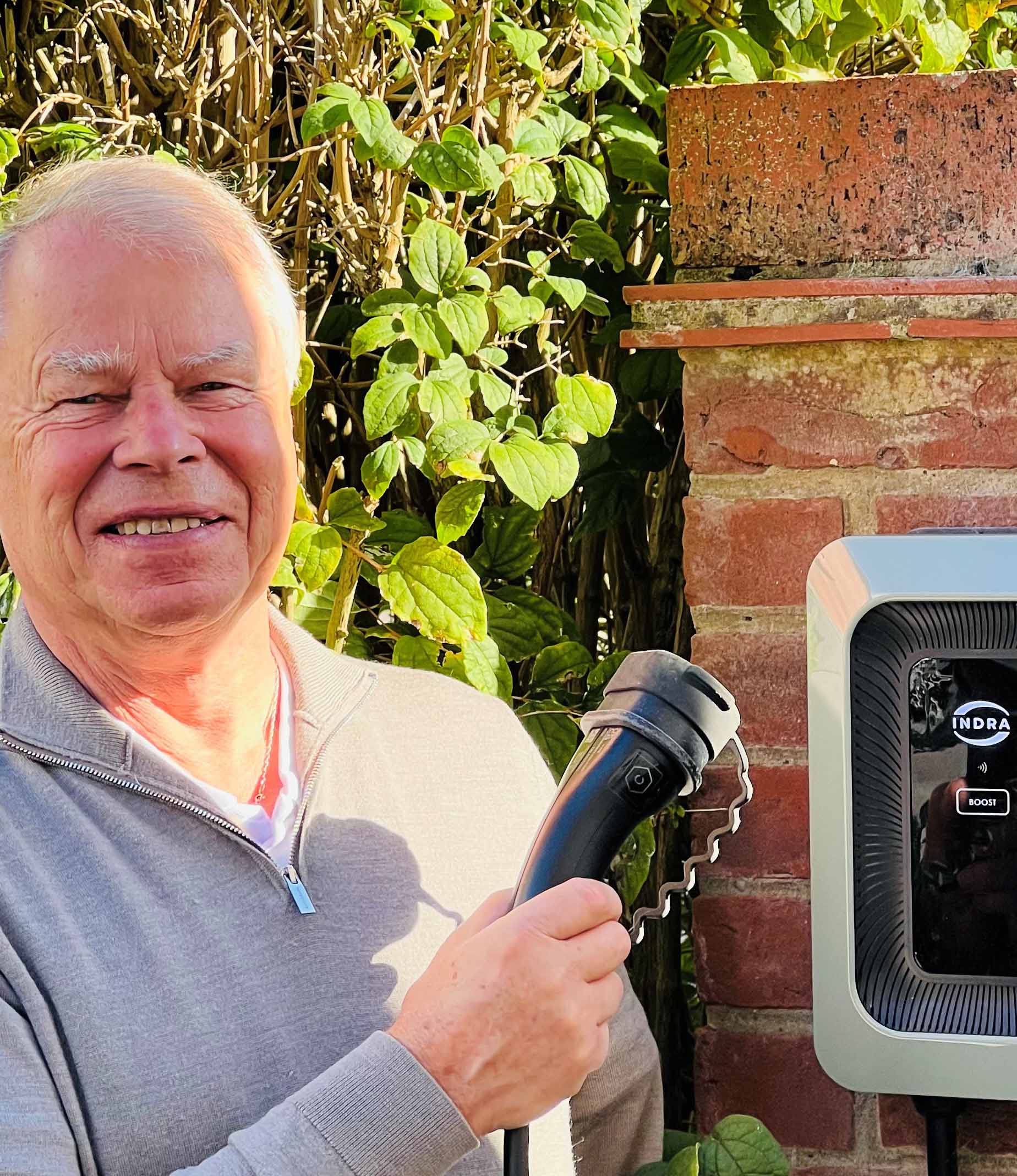Man holding charger plug next to Indra LUX on wall