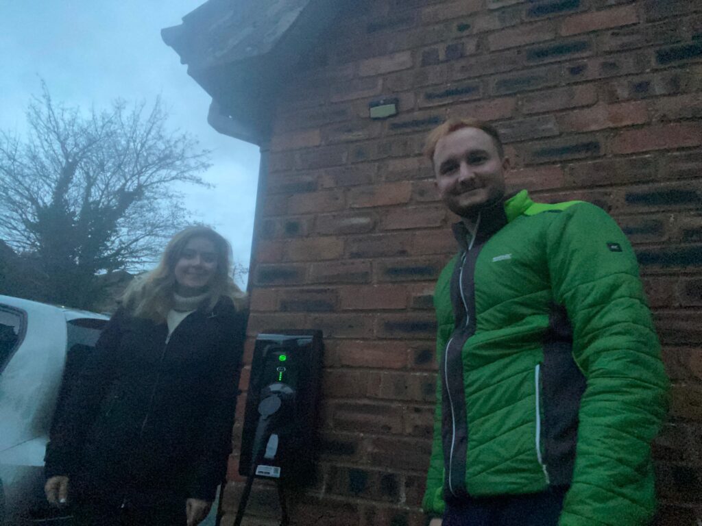 A couple standing by their EV charger